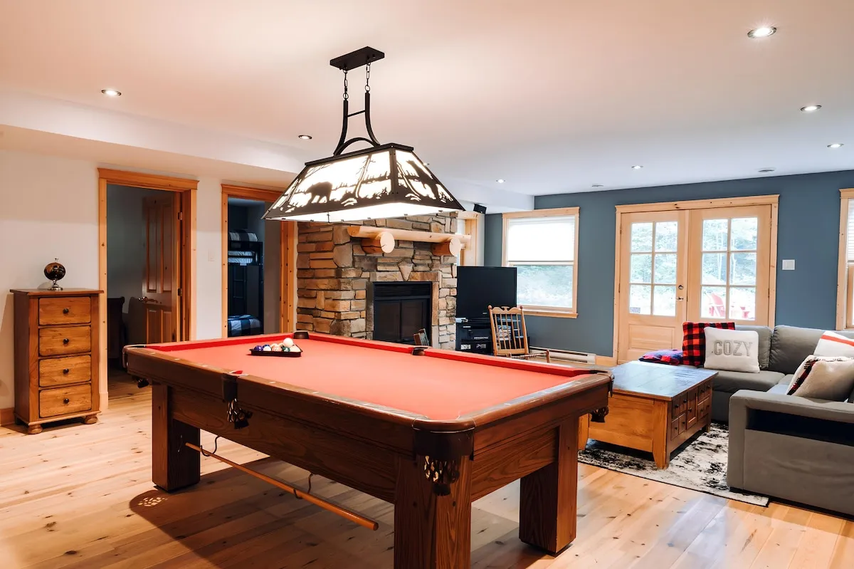 Salle de jeux et salon du chalet avec table de billard, foyer en pierre et espace détente pour des soirées conviviales.